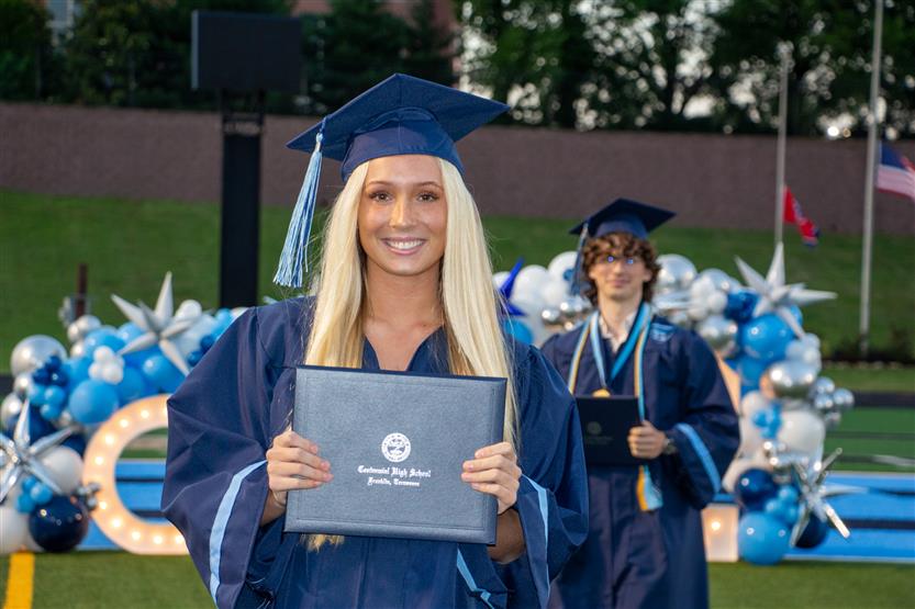 Students graduate outside on a football field